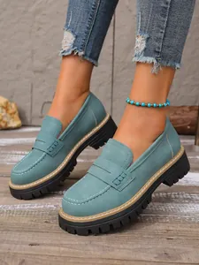 Close-up of vintage teal loafers featuring thick lug soles and elegant stitching
