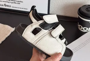 Nahaufnahme von schwarz-weißen Kindersandalen mit verstellbaren Klettverschlüssen.