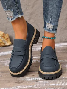 Detailed shot of dark blue matte platform loafers with chunky sole and white stitching