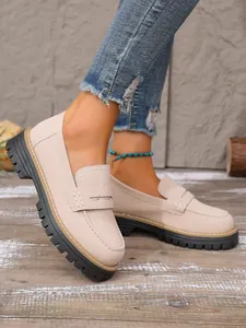 Detail of beige retro platform loafers with thick lug soles in a lifestyle setting