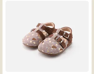 Close-up of girls floral hollow sandals with brown suede straps and buckles.