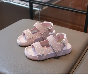 Rosa Kindersandalen mit weißen Punkten und verstellbaren Klettverschlussriemen.