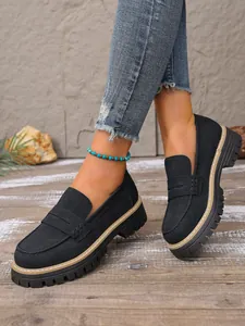 Close-up of vintage black frosted suede chunky platform loafers on feet.
