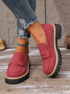 Close-up of vintage wine-red loafers with thick lug soles on a wooden floor surface.