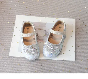 Detailed view of sparkly girls' princess shoes with rhinestone flowers and sequins.