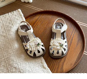 Close-up detail view of cream toddler sandals with delicate lace flower and soft flexible sole