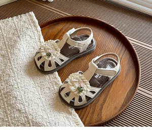 Detailed view of cream children's closed-toe sandals with floral lace and pearl accents