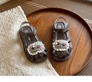 Close-up of children's brown closed-toe sandals with delicate lace floral decoration