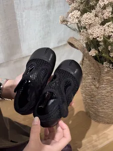 Dettaglio ravvicinato di scarpe Mary Jane in rete nera con punta divisa per bambine