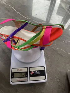 Detailed shot showing the 362g weight of a colorful strappy high-heeled sandal on a scale.