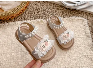 Detailansicht der silbernen Mädchensandalen mit Spitze, Perlenriemen und Karotten-Patches.
