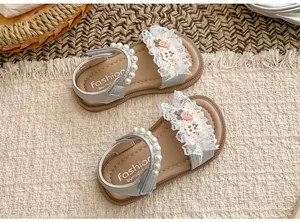Draufsicht auf elegante Mädchen-Sommersandalen mit Spitze, Perlen und niedlichen Karotten