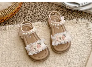Nahaufnahme von rosa Kleinkindsandalen mit eleganten Perlenriemen und Spitzenvolants
