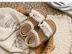 Detailansicht von rosa Mädchensandalen mit Perlenriemen und Spitzen-Karotten-Patches.