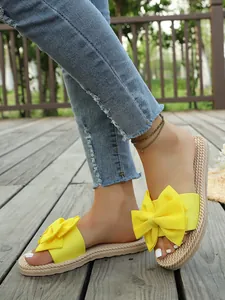 Dettaglio di ciabatte casual in lino giallo con fiocco su un pavimento di legno