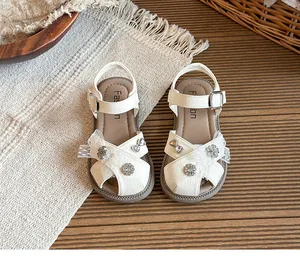 Detail of white girl's princess sandals with lace bow and rhinestone floral charms.