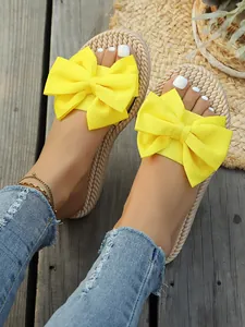 Dettaglio di ciabatte estive con fiocco giallo, suola in canapa intrecciata e design piatto comodo