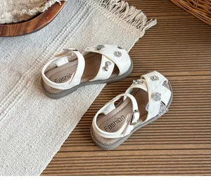 Close-up of white girls' hollowed princess sandals with floral and bow charms.
