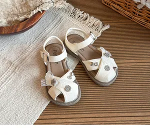 Close-up of white girl's princess sandals with delicate lace bows and flower charms