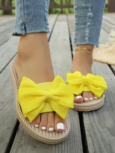 Primo piano di sandali con fiocco giallo brillante indossati su un ponte di legno
