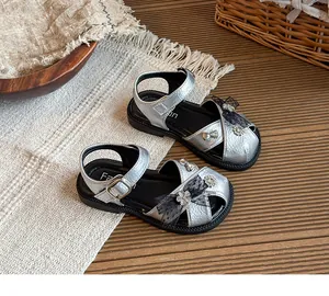 Detail of silver girls' sandals with glitter bow and flower embellishments