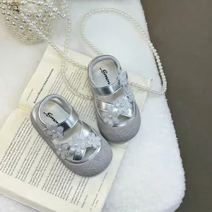 Eleganti sandali argento per bambine con fiori 3D su sfondo di un libro d'epoca decorato