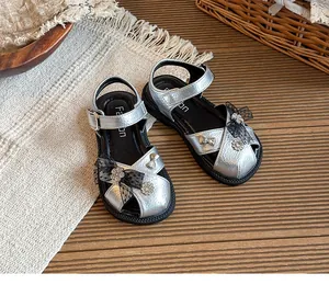 Silver metallic girl's sandals with black lace bows and sparkly rhinestone flowers.