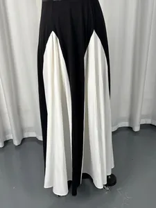 Close-up of an elegant black and white color-block maxi dress with pleated white panels.