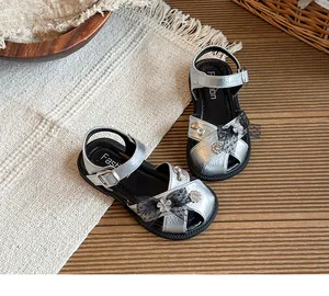 Detail view of silver girls' sandals featuring black lace bows and rhinestone flowers