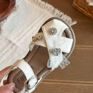 Elegant girls' beige princess sandals featuring lace bows and rhinestone flower details