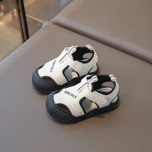 Sandales de marche blanches et noires pour tout-petits avec bout fermé et velcro.
