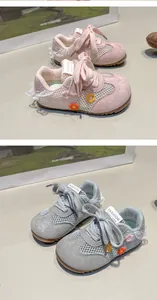 Gros plan de baskets pour tout-petits roses et grises avec broderies florales et dentelle.