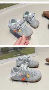 Détail de baskets grises pour tout-petits avec bordure en dentelle blanche et fleurs brodées