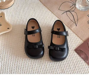 Gros plan de chaussures Mary Jane noires pour enfants avec nœuds sur tissu texturé