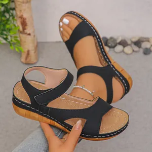Detailed view of women's black wedge sandals featuring platform soles and white stitching