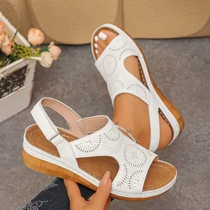 Eleganti sandali bianchi con zeppa da donna con motivi traforati al laser e cinturini velcro.