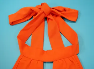 Detail van de oranje halternek-sluiting op deze sexy jumpsuit met open rug voor dames