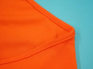 Close-up van de hoogwaardige stiksels en stoftextuur van de modieuze oranje jumpsuit.