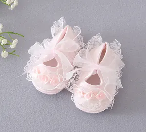 Detailed view of pink baby girl toddler shoes with delicate lace and ribbon bow