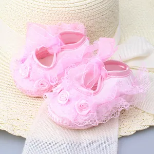 Close-up of pink baby princess lace shoes with delicate ribbon and flower details.