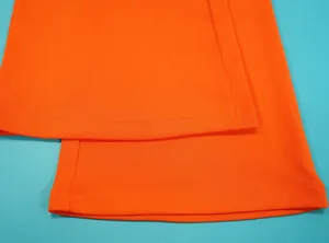 Detailopname van de dubbelgestikte zoom op feloranje stof van een jumpsuit.