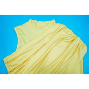 Detail view of a yellow pleated dress featuring textured mesh fabric and a mock neck