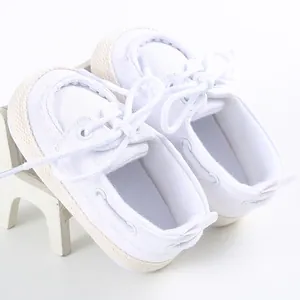 Dettaglio di scarpe in tela bianche per neonati con suola morbida e lacci