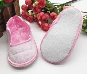 Close-up of pink soft-sole baby shoes with lace trim and non-slip bottom
