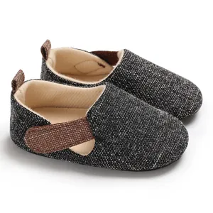 Detalle de zapatos de bebé para caminar en tela moteada gris con detalles marrones.