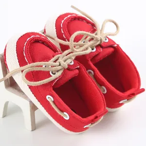 Dettaglio di scarpe di tela rosse per neonati con suola morbida e lacci decorativi.
