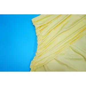 Detailed macro view showing side ruching on a yellow mesh slim fit mini dress