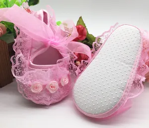 Detailed view of pink lace baby walker shoes with non-slip soft soles and ribbon roses