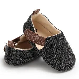 Vista detallada de zapatos para bebés de tela gris con una correa marrón de sujeción