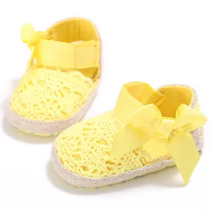 Gros plan sur des chaussures de marche pour bébé en dentelle jaune avec un gros nœud